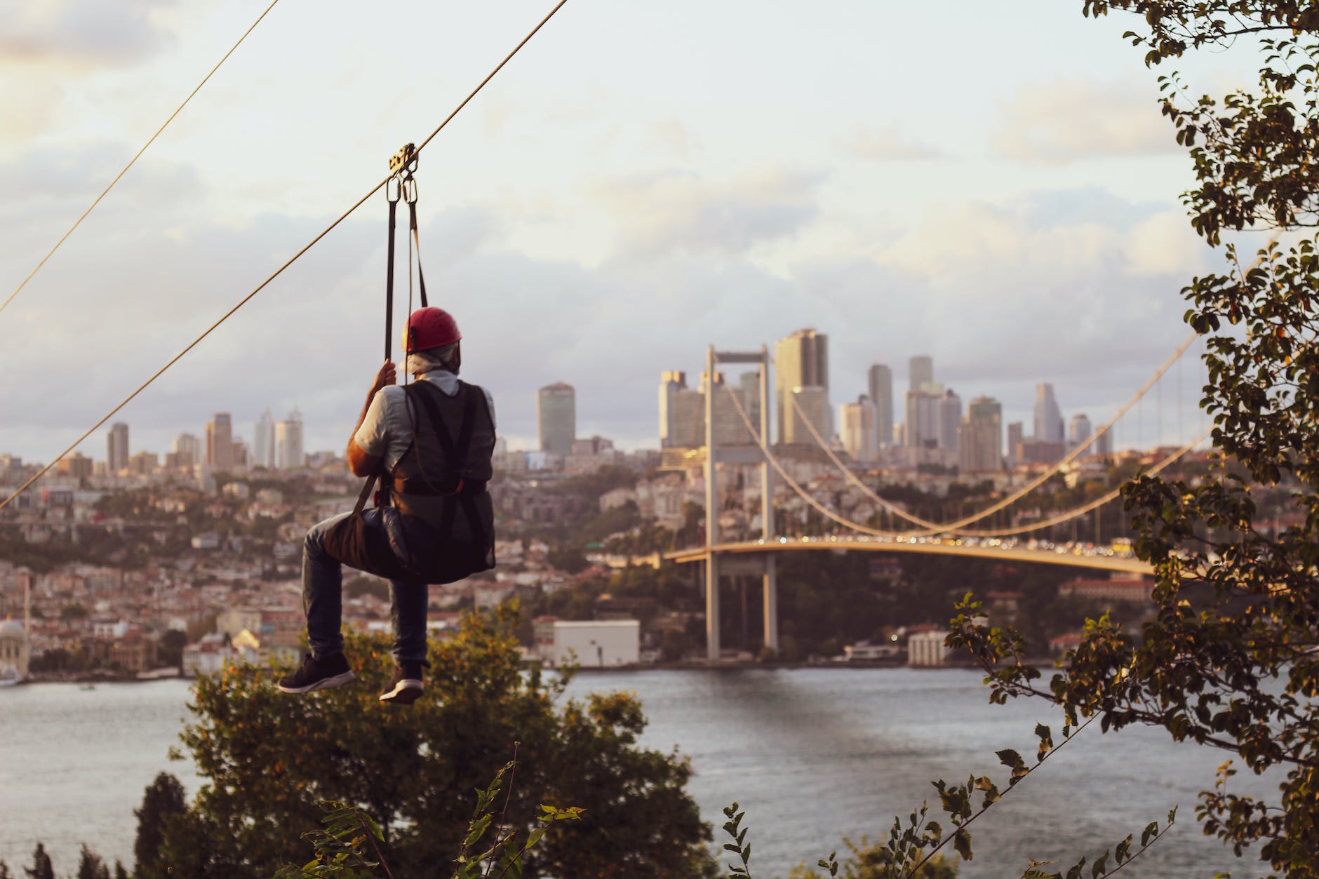 a man riding a zipline wit ha view of a city